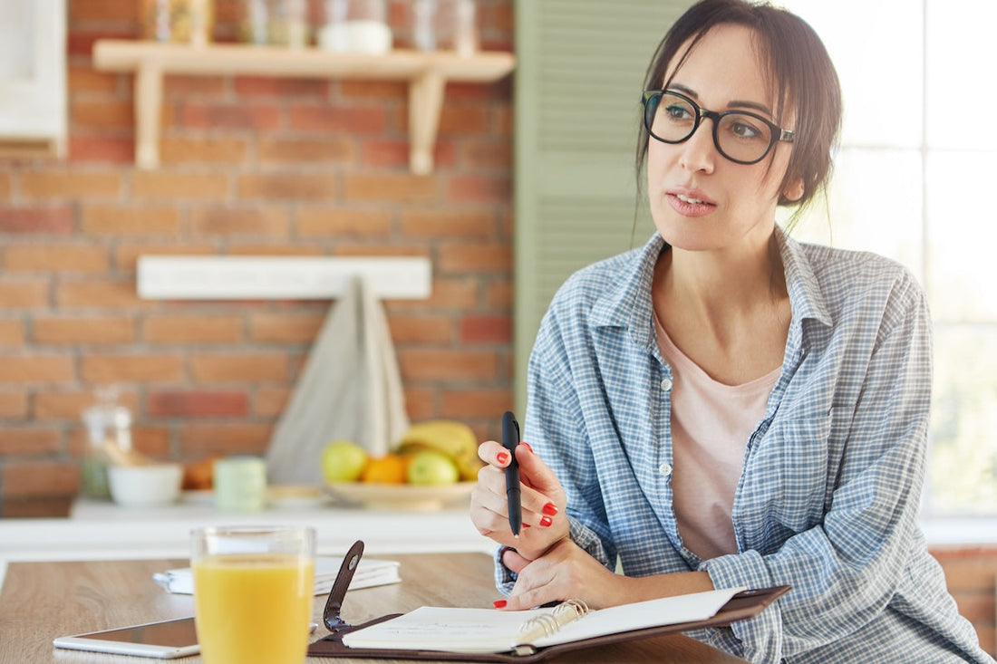 young woman planning her day at kitchen bench with diary